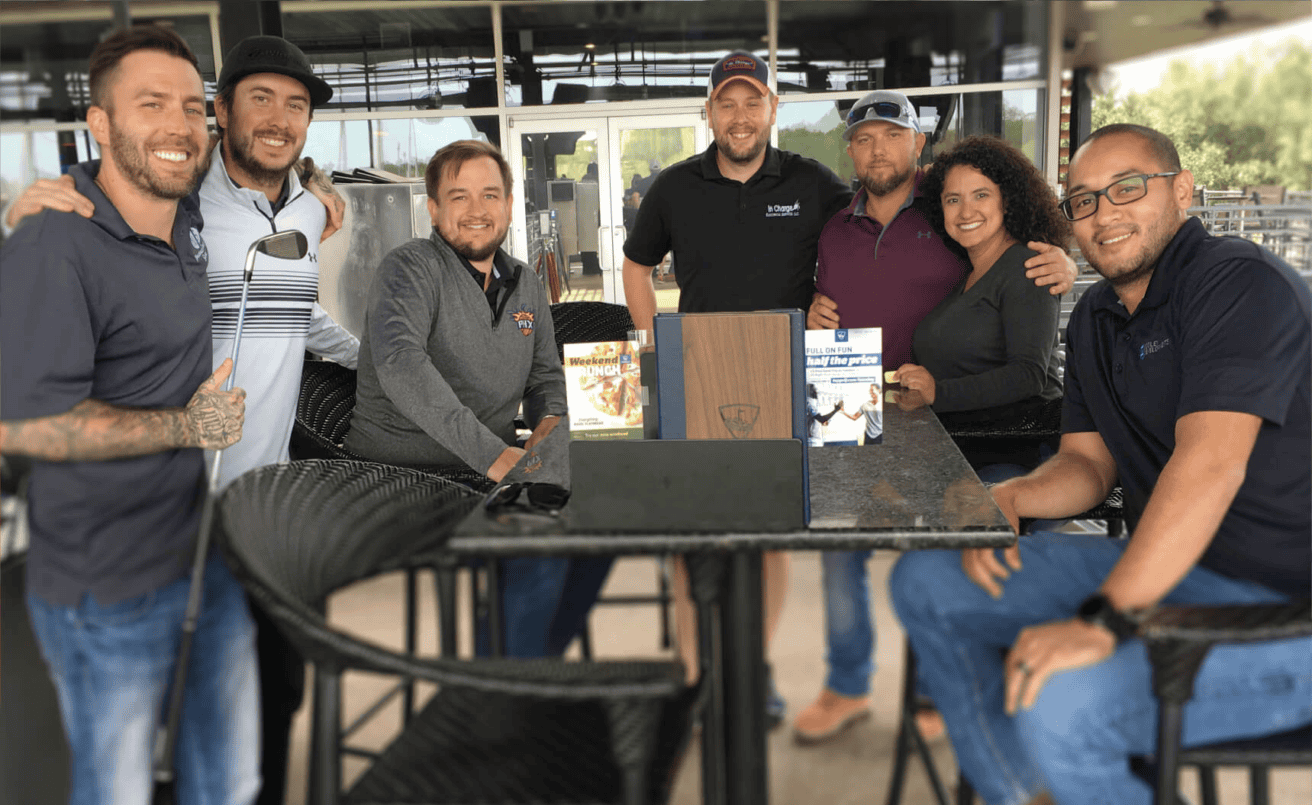 A group of people posing at an outdoor table for a photo.
