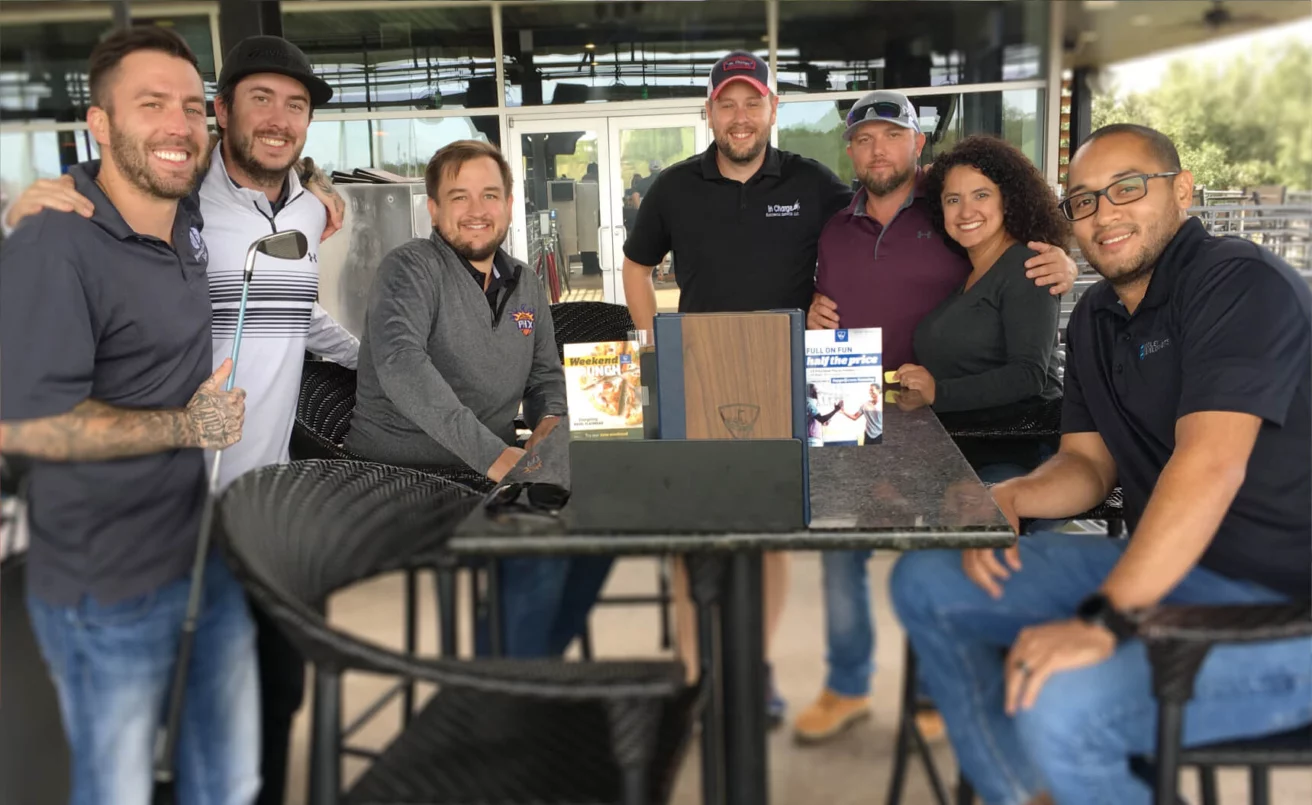 A group of people posing at an outdoor table for a photo.