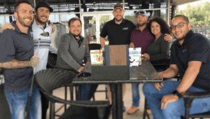 A group of people posing at an outdoor table for a photo.