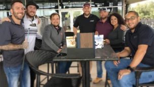 A group of people posing at an outdoor table for a photo.