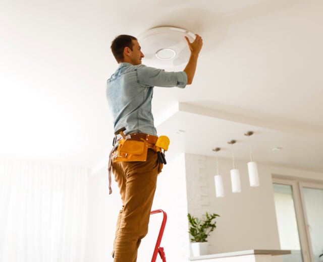 Technician installing a new light fixture in a residential home.