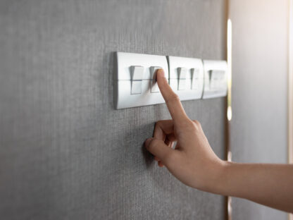 An image focusing on a hand turning off a light switch.