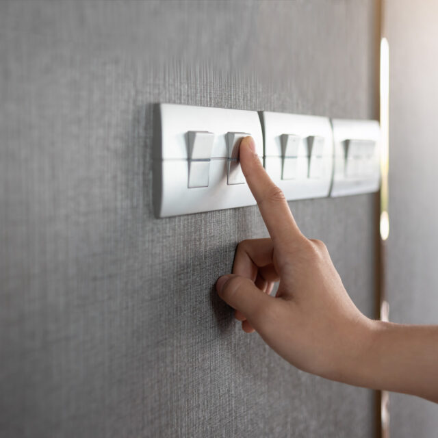 An image focusing on a hand turning off a light switch.